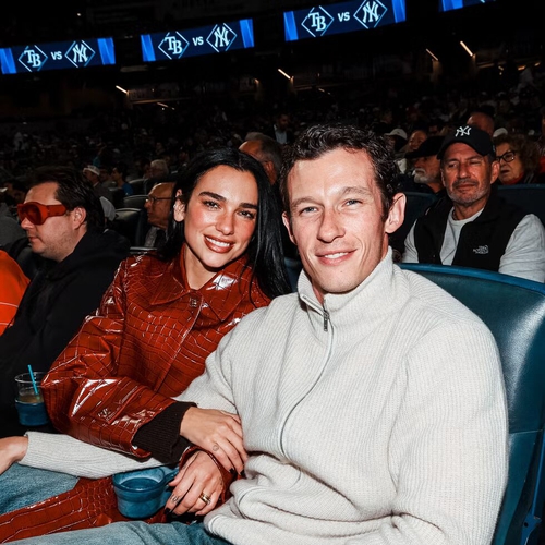 Gaya Dua Lipa Saat Menonton Yankees dengan Mantel Kulit Buaya Burgundy Koleksi Chanel Métiers d’Art